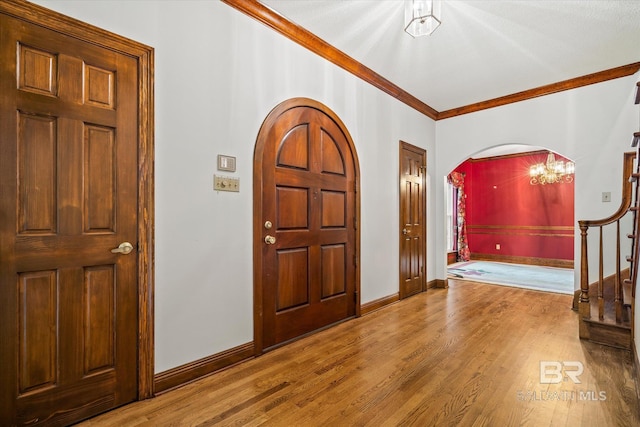 entrance foyer featuring crown molding, hardwood / wood-style floors, and a notable chandelier