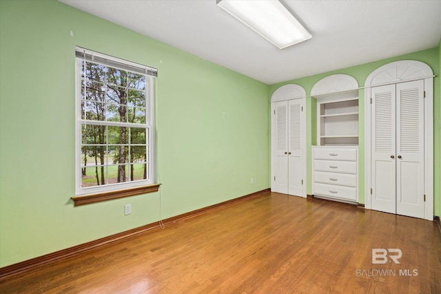 3761 Winford Rd, Mobile, AL 36619 - unfurnished bedroom featuring two closets, baseboards, and wood finished floors