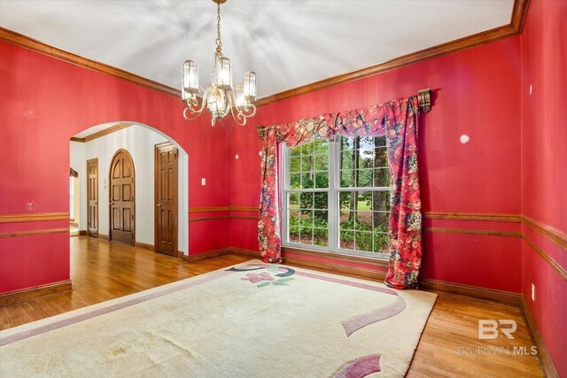 empty room with hardwood / wood-style floors, a chandelier, and ornamental molding