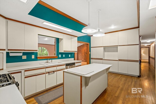 kitchen featuring hanging light fixtures, a center island, light hardwood / wood-style flooring, sink, and ornamental molding