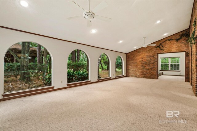 unfurnished living room with carpet flooring, ceiling fan, brick wall, and a healthy amount of sunlight