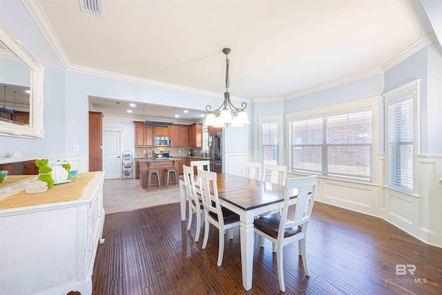 8856 Asphodel Ln, Daphne, AL 36526 - dining space featuring dark wood-style flooring, ornamental molding, a decorative wall, a chandelier, and a wainscoted wall
