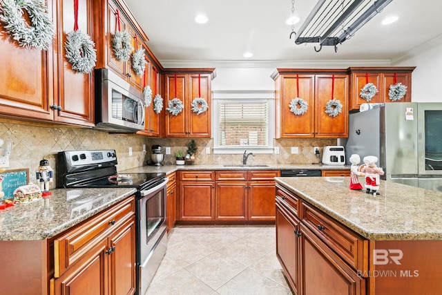 kitchen with appliances with stainless steel finishes, ornamental molding, sink, light tile patterned floors, and a kitchen island