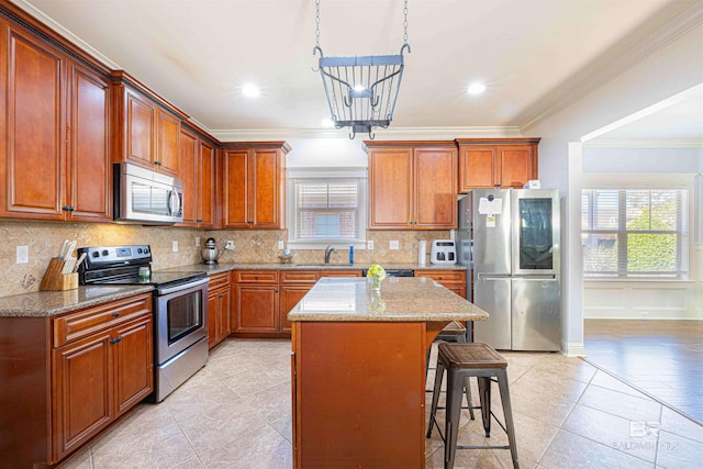 8856 Asphodel Ln, Daphne, AL 36526 - kitchen with stainless steel appliances, ornamental molding, plenty of natural light, a kitchen island, and a kitchen breakfast bar