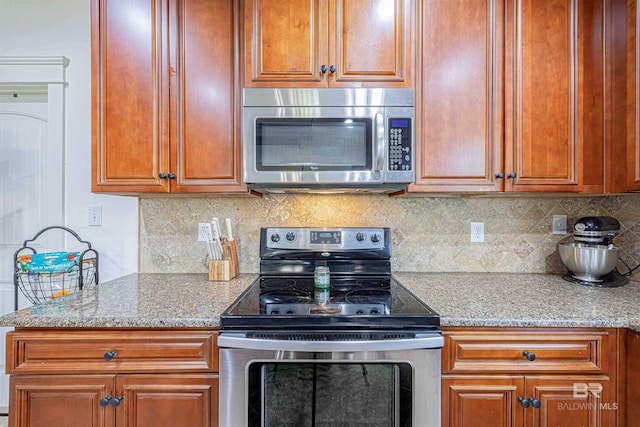 8856 Asphodel Ln, Daphne, AL 36526 - kitchen with stainless steel appliances, light stone counters, tasteful backsplash, and brown cabinets