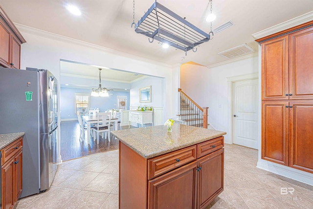 8856 Asphodel Ln, Daphne, AL 36526 - kitchen with freestanding refrigerator, light tile patterned floors, crown molding, light stone countertops, and a center island