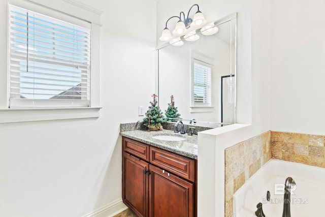 bathroom with a bath, vanity, plenty of natural light, and a notable chandelier