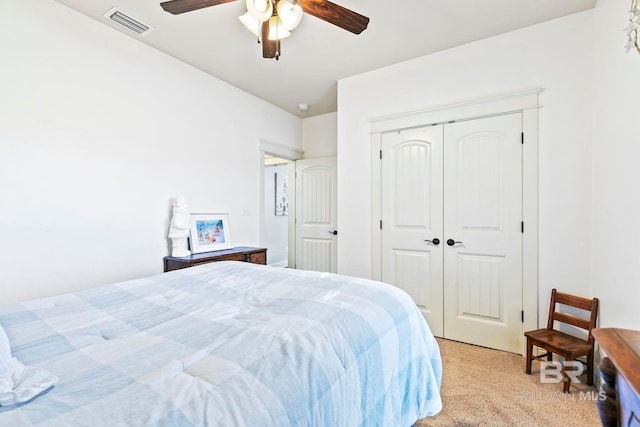 bedroom with ceiling fan, light carpet, and a closet