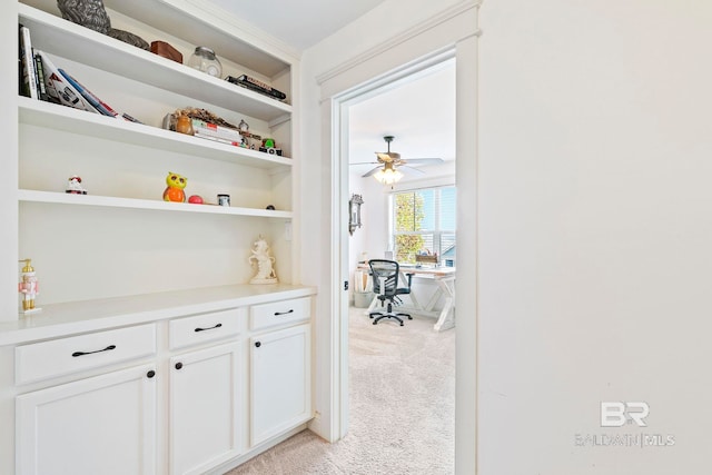 interior space featuring light carpet, white cabinets, and ceiling fan