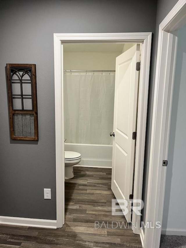 full bathroom featuring toilet, wood finished floors, baseboards, and shower / bathtub combination with curtain