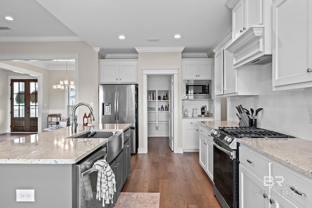 kitchen with appliances with stainless steel finishes, a center island with sink, white cabinets, and light stone counters