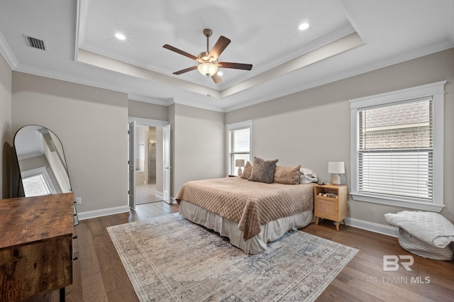 bedroom featuring dark hardwood / wood-style flooring, a tray ceiling, crown molding, and ceiling fan