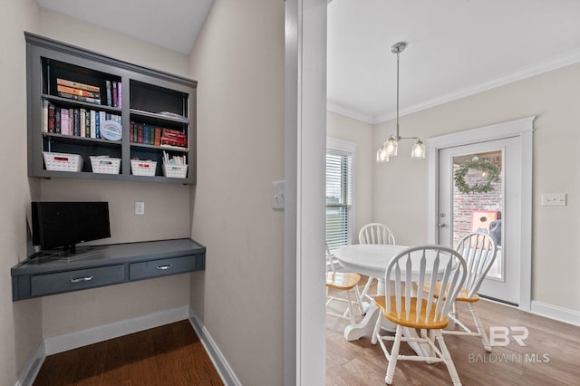 dining area with crown molding, built in desk, hardwood / wood-style floors, and a notable chandelier