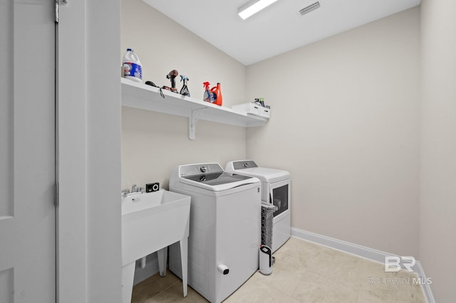 laundry area with separate washer and dryer and sink