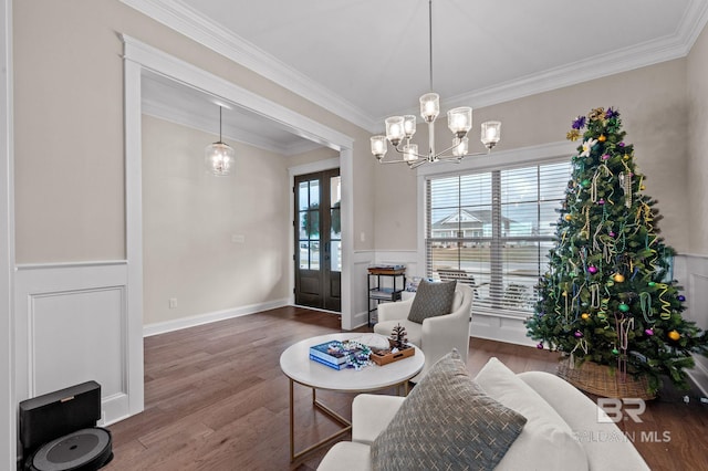 living area with hardwood / wood-style flooring, ornamental molding, and a notable chandelier