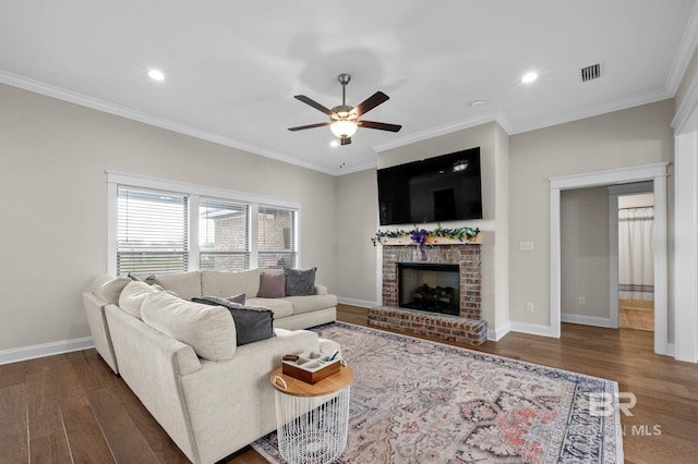 living room featuring a fireplace, crown molding, dark wood-type flooring, and ceiling fan