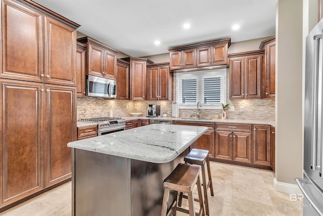 607 Wedgewood Dr, Gulf Shores, AL 36542 - kitchen featuring appliances with stainless steel finishes, a sink, tasteful backsplash, light stone counters, and a breakfast bar area