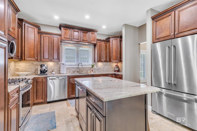 607 Wedgewood Dr, Gulf Shores, AL 36542 - kitchen with appliances with stainless steel finishes, a sink, backsplash, light stone countertops, and a kitchen island