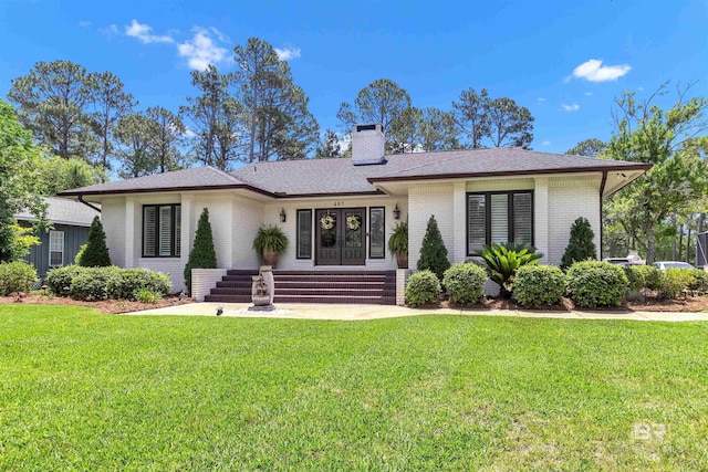 607 Wedgewood Dr, Gulf Shores, AL 36542 - view of front of property featuring brick siding, a front lawn, a chimney, roof with shingles, and french doors