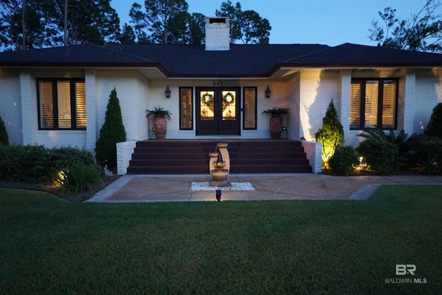 607 Wedgewood Dr, Gulf Shores, AL 36542 - view of front facade featuring brick siding, a front yard, a chimney, and french doors