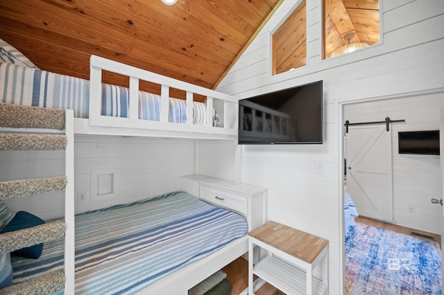 bedroom featuring wood ceiling, wooden walls, lofted ceiling, and a barn door