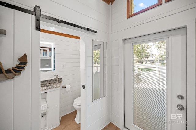 bathroom with wood-type flooring, toilet, and wood walls