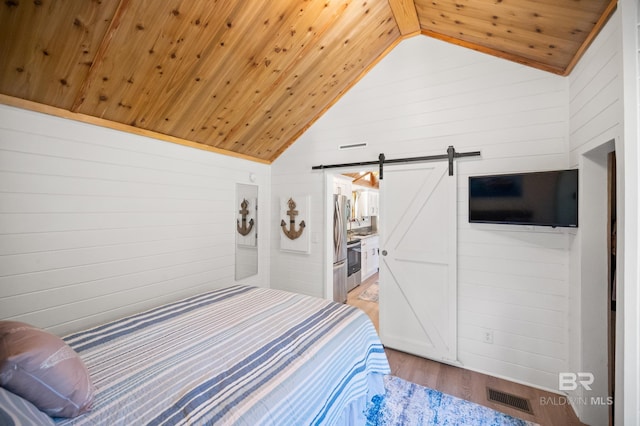 bedroom featuring lofted ceiling, wood walls, wooden ceiling, a barn door, and hardwood / wood-style floors