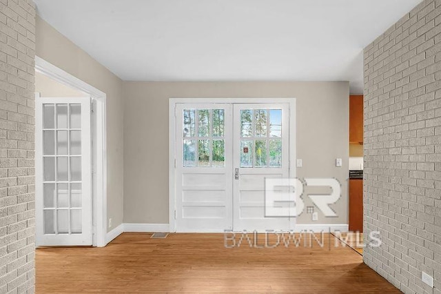 doorway to outside featuring light hardwood / wood-style floors and brick wall