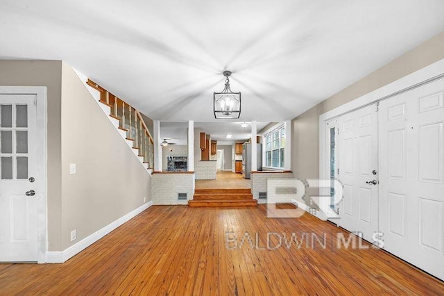 foyer with a brick fireplace, ceiling fan with notable chandelier, and light hardwood / wood-style flooring