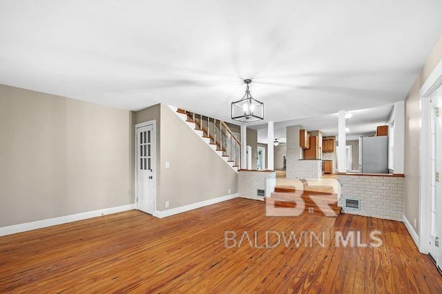 unfurnished living room with an inviting chandelier and hardwood / wood-style flooring