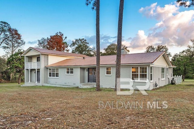 rear view of house with a yard and a balcony