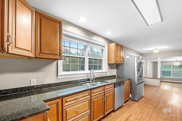 kitchen featuring dark stone countertops, light wood-type flooring, sink, and appliances with stainless steel finishes