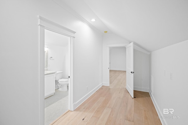 hallway with light hardwood / wood-style floors and vaulted ceiling