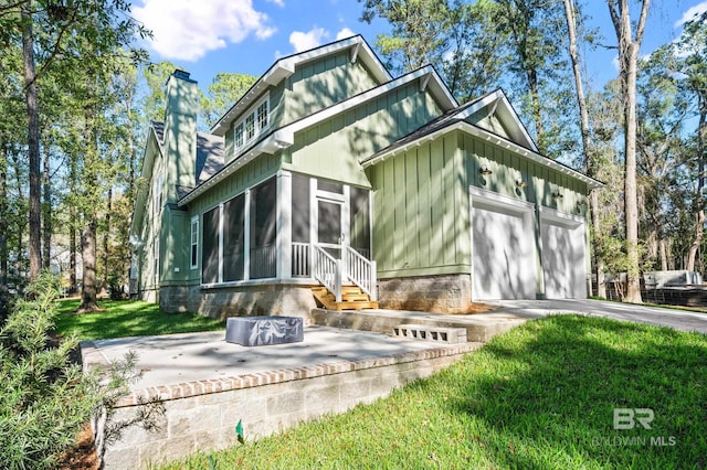 back of property with a sunroom, a garage, and a yard