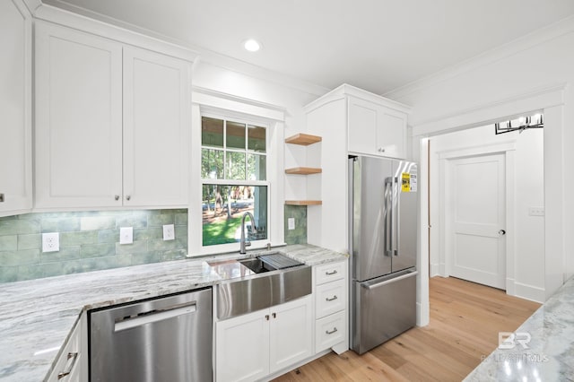 kitchen featuring light stone countertops, sink, stainless steel appliances, white cabinets, and light wood-type flooring