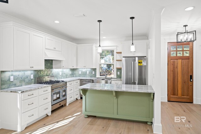 kitchen featuring pendant lighting, custom exhaust hood, a center island, white cabinetry, and stainless steel appliances