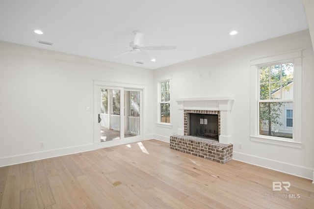 unfurnished living room with a brick fireplace, ceiling fan, crown molding, and light wood-type flooring