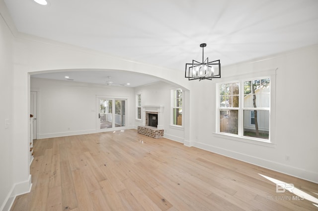 unfurnished living room featuring a brick fireplace, light hardwood / wood-style flooring, a wealth of natural light, and crown molding