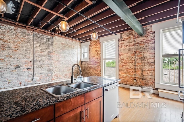 kitchen with dark stone countertops, sink, stainless steel dishwasher, and a wealth of natural light