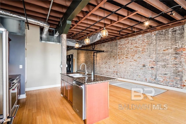 kitchen with sink, dark stone counters, stove, stainless steel dishwasher, and light hardwood / wood-style flooring