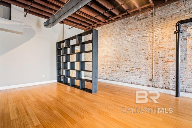 basement featuring hardwood / wood-style flooring and brick wall