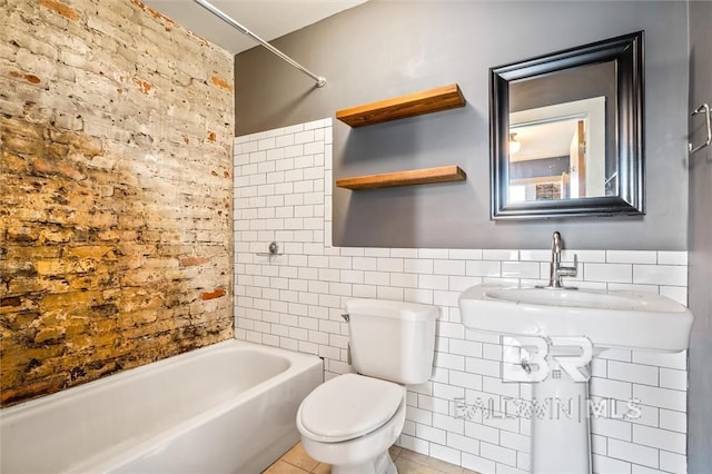 full bathroom featuring sink, tile walls, tile patterned flooring, toilet, and washtub / shower combination