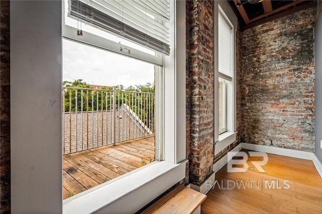 doorway to outside featuring hardwood / wood-style floors, plenty of natural light, and brick wall