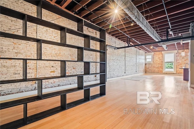 interior space featuring hardwood / wood-style flooring, a towering ceiling, and brick wall