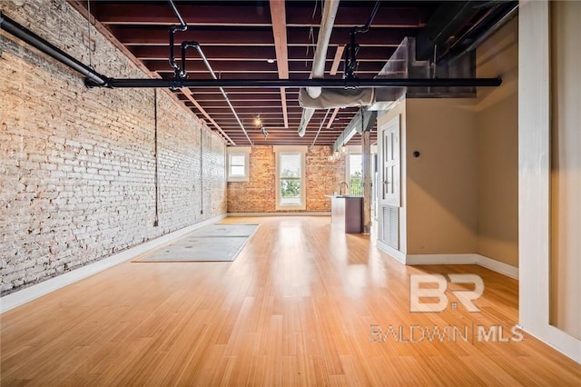 basement with hardwood / wood-style flooring, brick wall, and sink