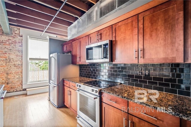 kitchen with appliances with stainless steel finishes, light wood-type flooring, decorative backsplash, and dark stone counters