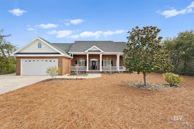 neoclassical / greek revival house with gravel driveway, brick siding, a porch, and an attached garage