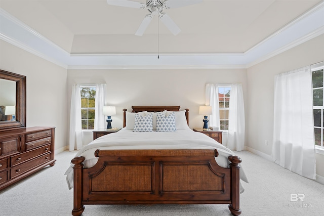 bedroom with a tray ceiling, baseboards, light colored carpet, and ornamental molding