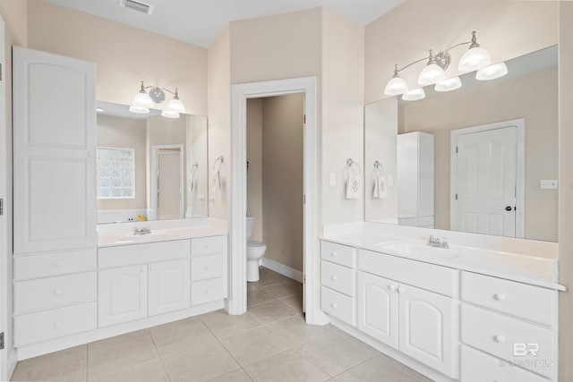 full bath with a sink, toilet, two vanities, and tile patterned floors