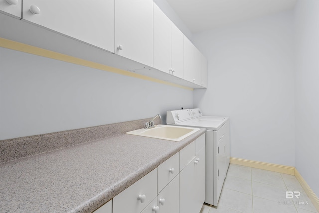 laundry area with baseboards, washing machine and dryer, light tile patterned floors, cabinet space, and a sink